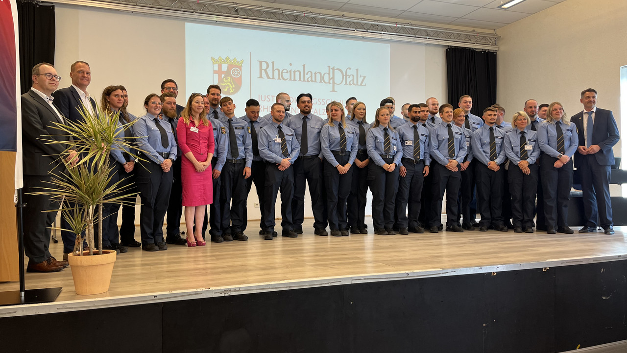 Das Bild zeigt: Die Absolventinnen und Absolventen der Justizvollzugsschule Rheinland-Pfalz mit Justizminister Philipp Fernis, Staatssekretär Dr. Jens Diener und Frau Kunz-de Boer.