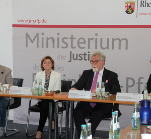 Herr Stefan Thum, Frau Dr. Elisabeth Volk, Justizminister Herbert Mertin und Frau Dr. Corinna Zellmann vor einer Pressewand