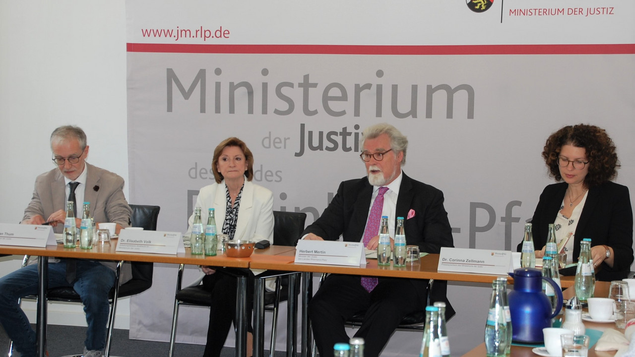 Herr Stefan Thum, Frau Dr. Elisabeth Volk, Justizminister Herbert Mertin und Frau Dr. Corinna Zellmann vor einer Pressewand