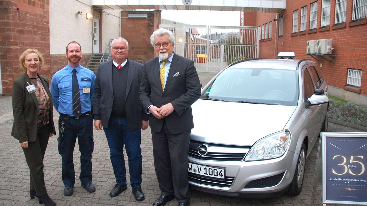 Gruppenfoto von Gabriele Graf, Daniel Riegel, Jürgen Buchholz und Justizminister Herbert Mertin vor einem Fahrschulauto der JVA 