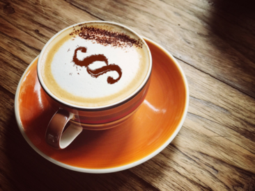 Cappuccino in einer Tasse mit einem §-Zeichen aus Kakao auf dem Milchschaum